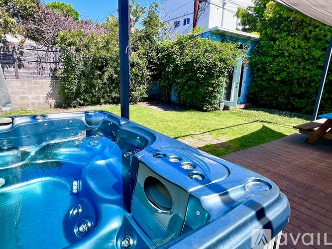 A hot tub sits on a deck in a backyard.