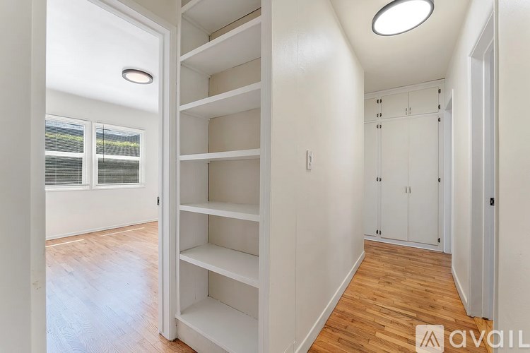 A white room with a wooden floor and a window.