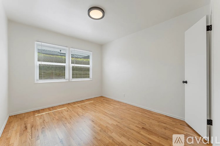 A room with wooden flooring and a window with blinds.