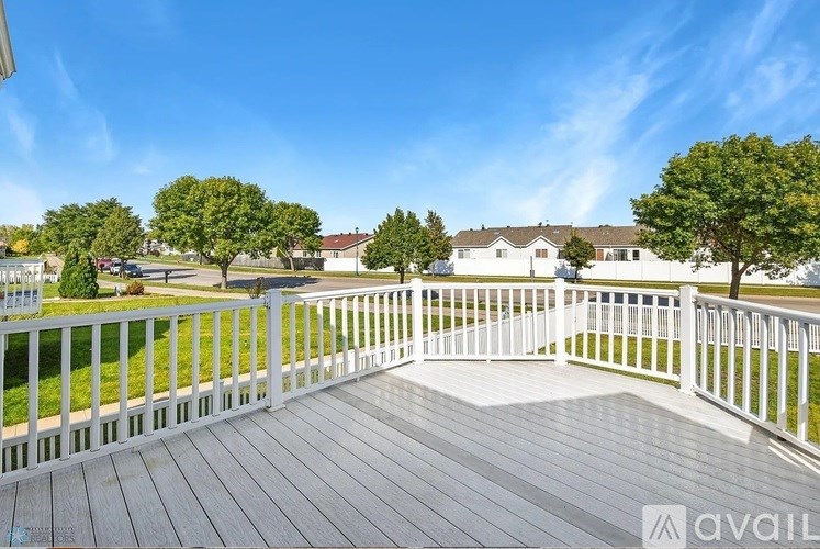 A deck with a white railing and a view of a residential area.