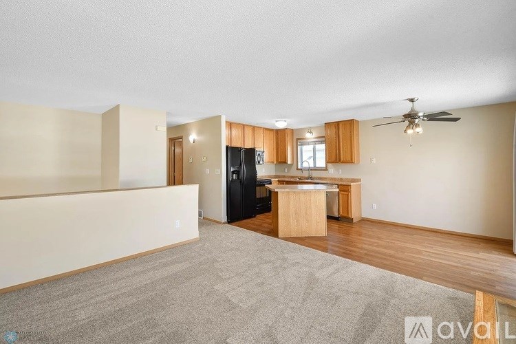 A spacious living room with a kitchen area in the background.