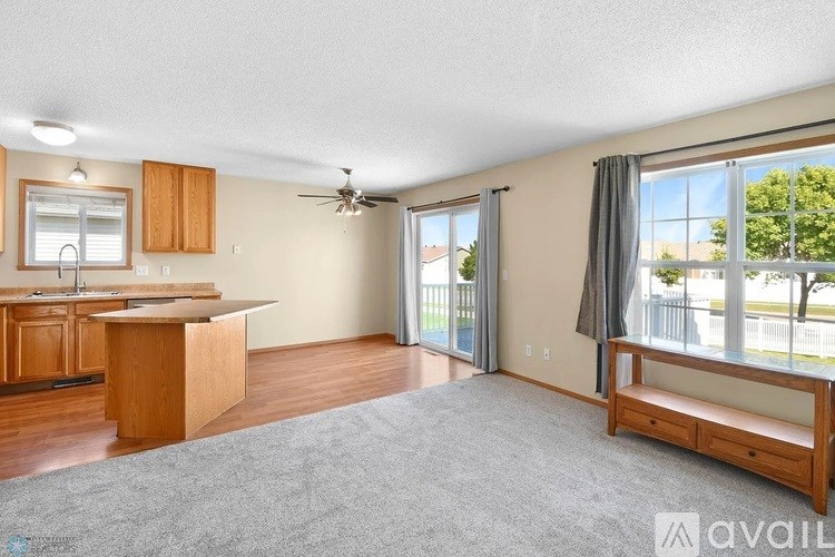 A spacious living room with a kitchen area and sliding glass doors.