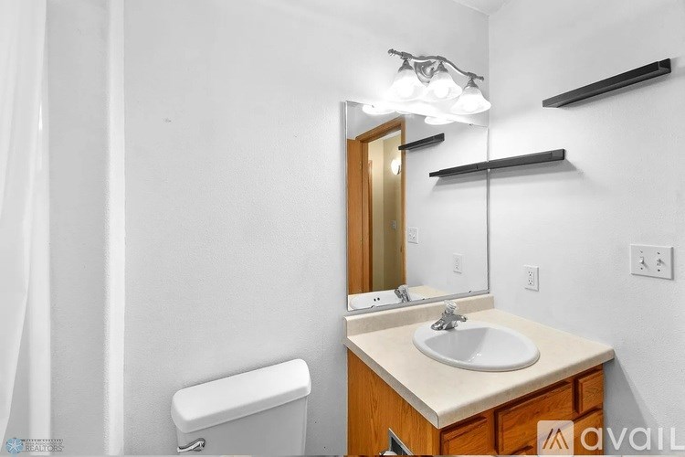 A bathroom with a sink, mirror, and toilet paper holder.