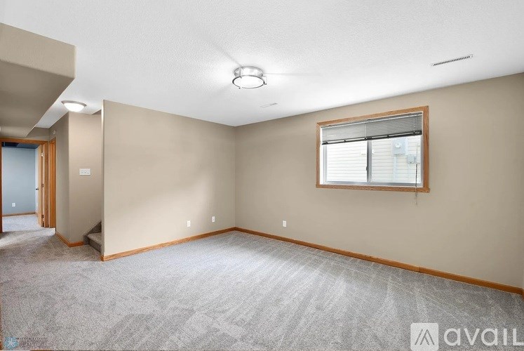 A room with a window and a carpeted floor.