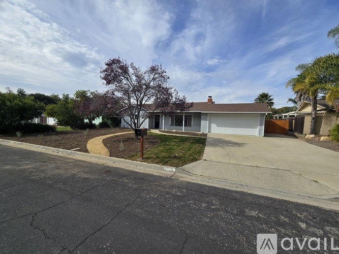 A house with a driveway and a tree in front.