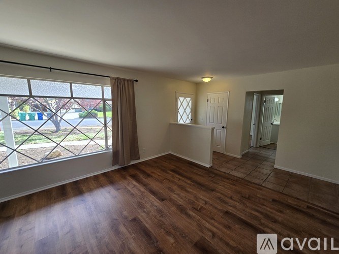 A room with wooden floors and a large window overlooking a street.