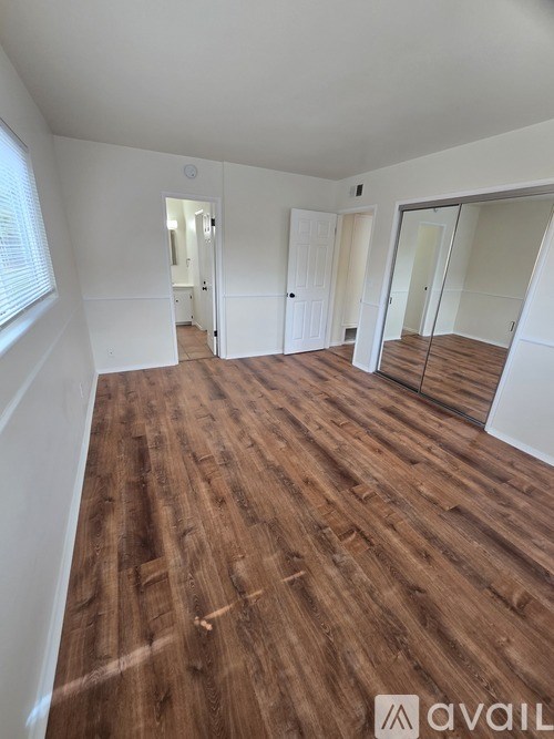 A room with wooden flooring and white walls.