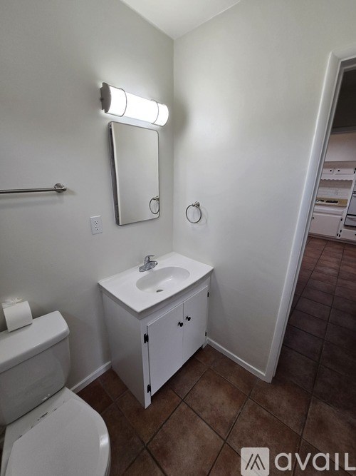 A bathroom with a toilet, sink, and mirror.