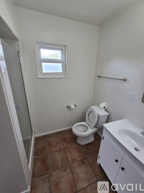 A bathroom with a toilet, sink, and window.