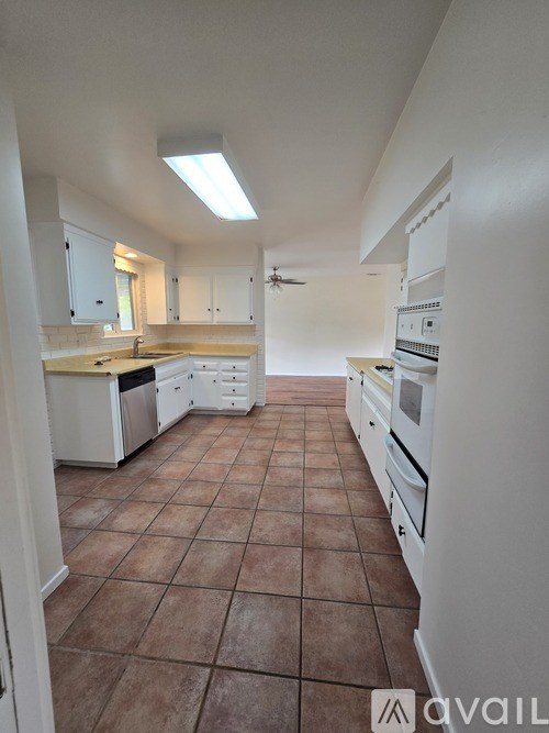 A kitchen with white appliances and brown tile flooring.