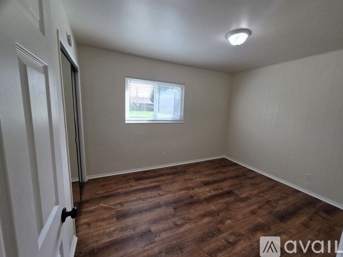 A room with wooden flooring and a window.