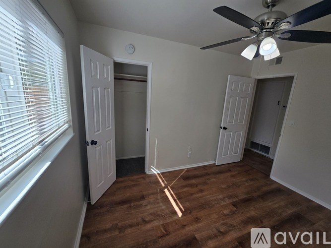 A room with a ceiling fan and wooden flooring.