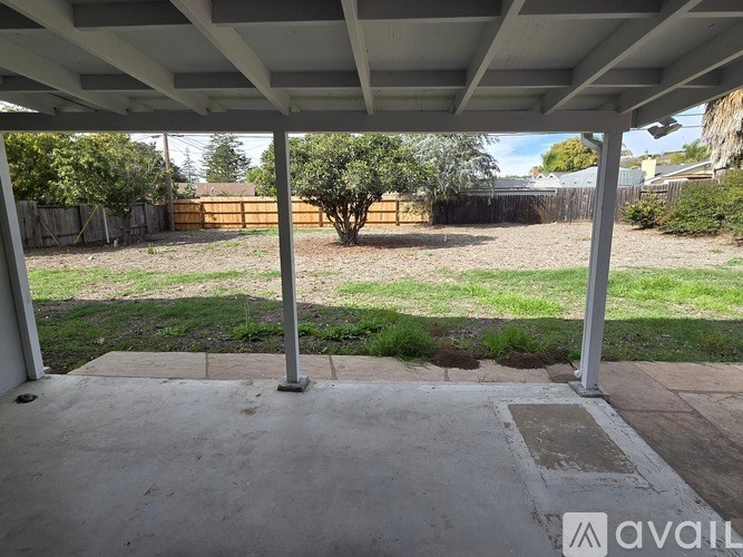A patio with a concrete floor and a white pergola over it.