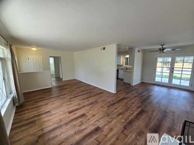 A spacious room with wooden flooring and white walls.
