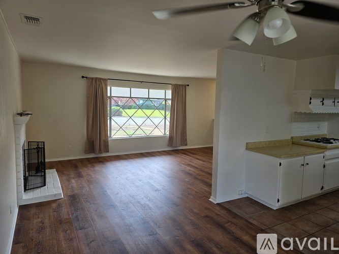 A living room with a fireplace and a kitchen area in the background.