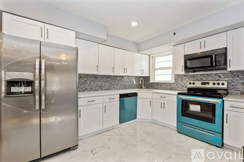 A kitchen with a stainless steel refrigerator, white cabinets, and a blue oven.