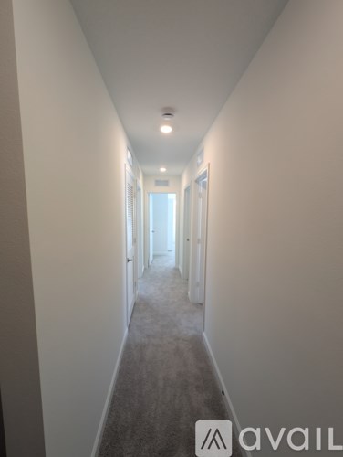 A long hallway with a carpeted floor and white walls.