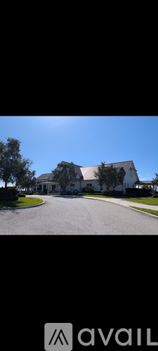A house with a white exterior and a grey roof is surrounded by a green lawn and trees.