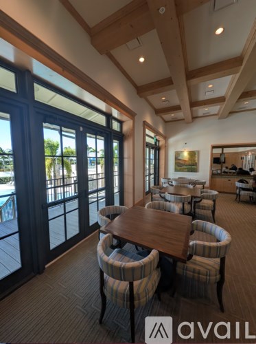 A room with a long table and chairs with striped cushions.