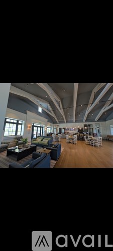 A spacious room with wooden floors and multiple seating arrangements.