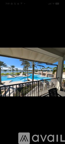 A balcony with a pool and palm trees in the distance.
