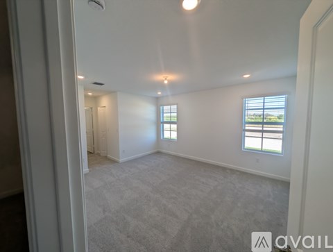 A spacious room with a window and carpeted floor.