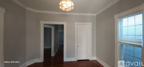 A room with a chandelier and a door leading to another room.
