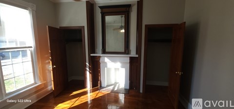 A room with a large mirror and wooden floors.