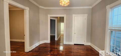 A room with a chandelier and a doorway leading to another room.