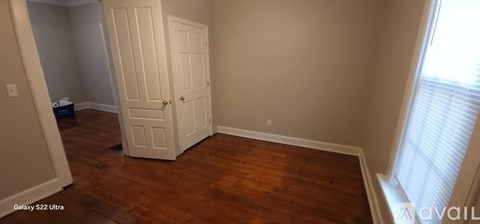 A room with a white door and wooden floors.