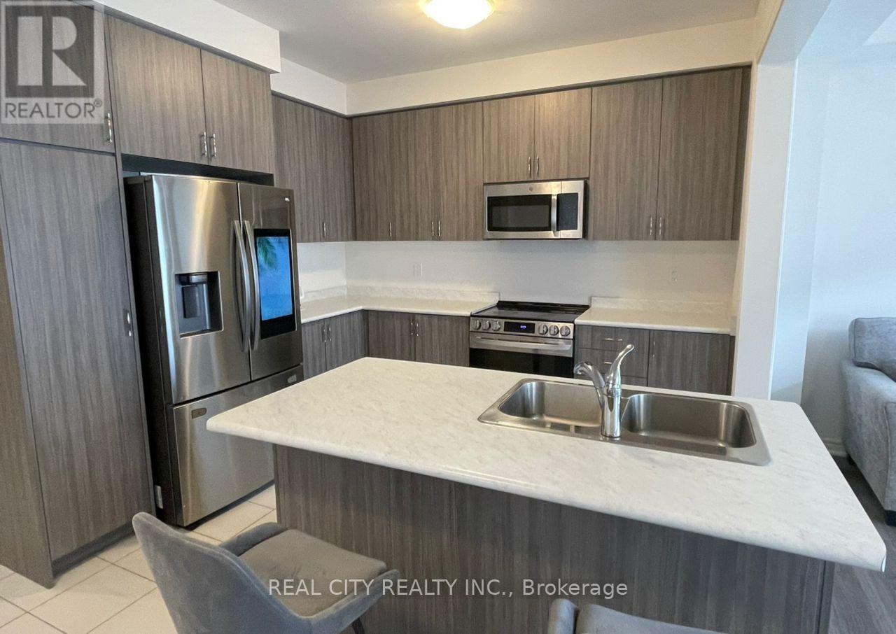 A kitchen with a refrigerator, microwave, oven, sink and a counter.