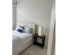A bedroom with a white bed and a small wooden table.