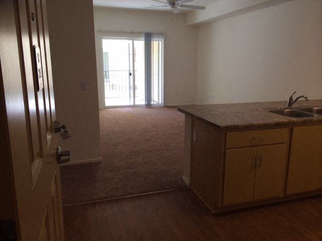 an empty kitchen and living room with a door to a balcony