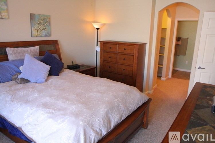 A bedroom with a large bed and a lamp.