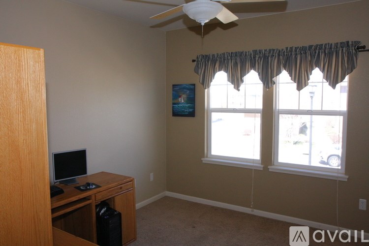 A room with a desk and a fan.