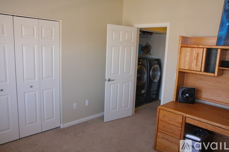 A room with a washing machine and a wooden cabinet.