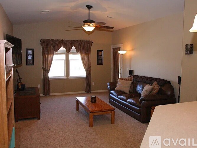 A living room with a brown couch, a coffee table, and a ceiling fan.