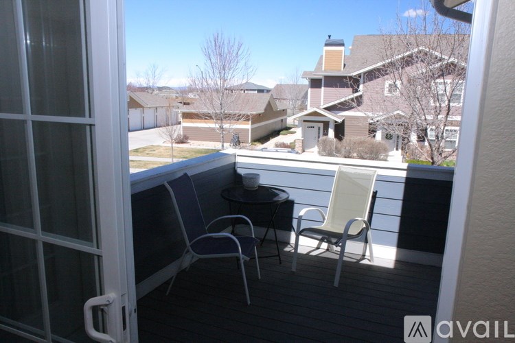 A balcony with a table and chairs overlooking a residential area.