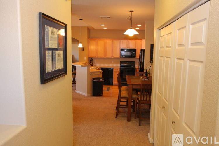 A kitchen with a framed picture on the wall and a dining table with chairs.