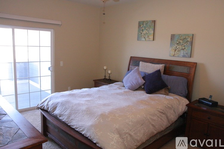 A bedroom with a bed, nightstand, and two paintings on the wall.