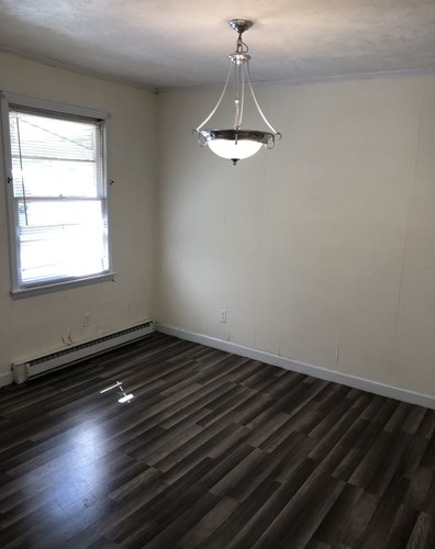 A room with a wooden floor and a chandelier hanging from the ceiling.