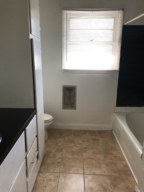 A bathroom with a toilet, sink, and window.