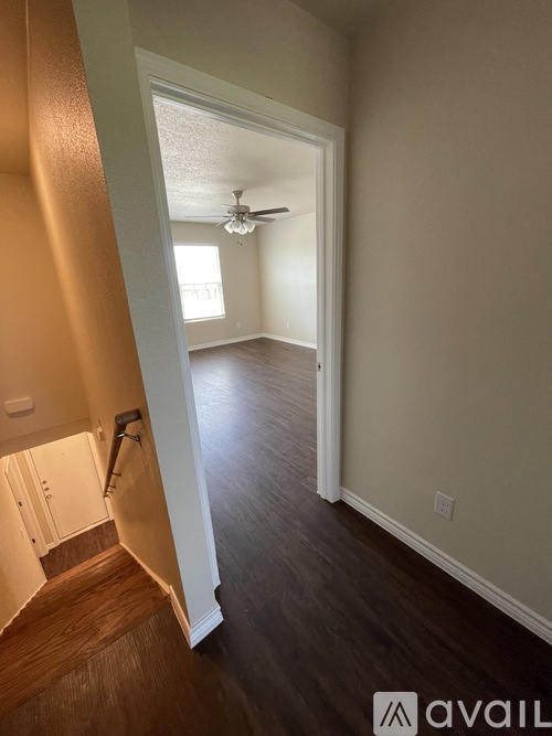 A hallway with a wooden floor and a ceiling fan.