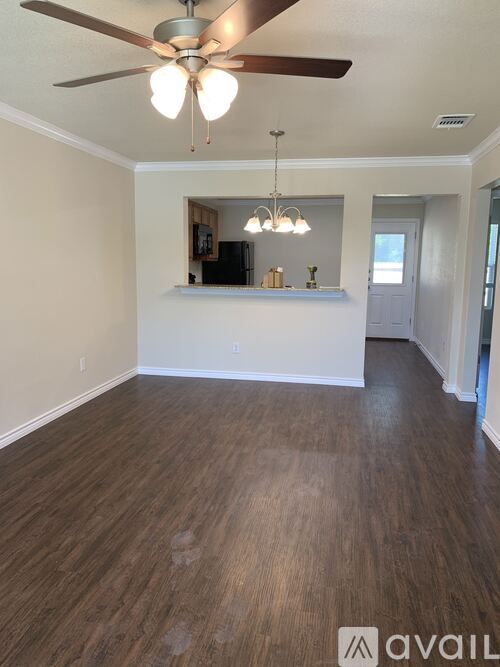 A room with a ceiling fan and wooden flooring.