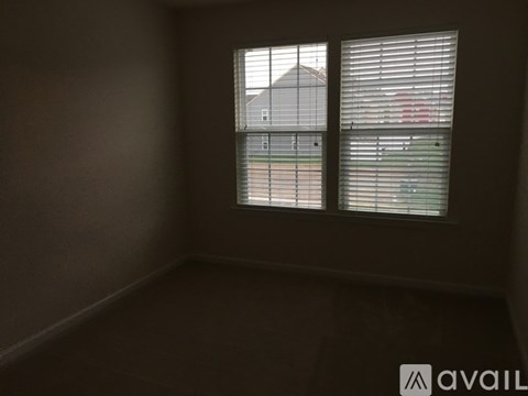 A room with a window showing a fence and a house.
