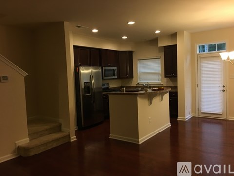 A kitchen with dark brown cabinets and a black refrigerator.