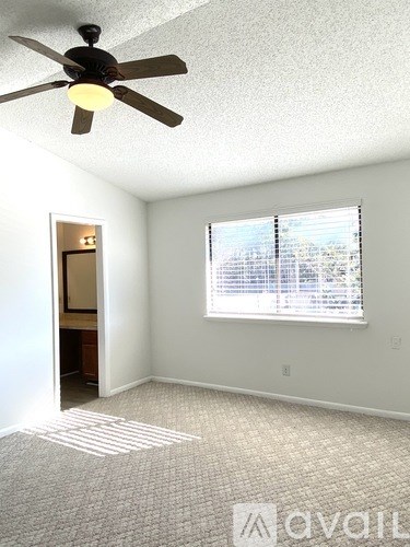 A room with a ceiling fan and a window with blinds.