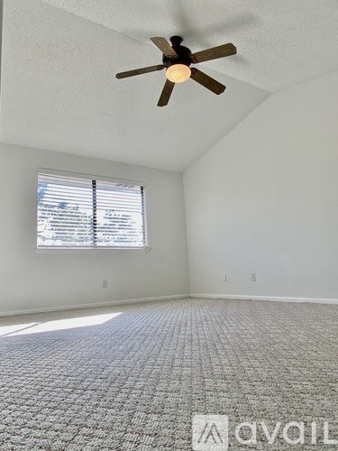 A room with a ceiling fan and a window with blinds.