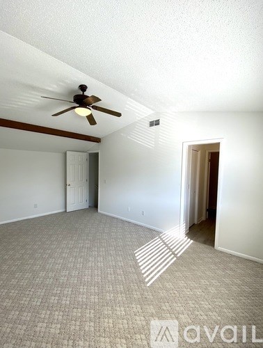 A room with a ceiling fan and carpeted floor.