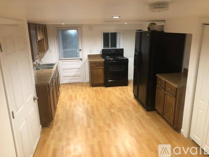 A kitchen with wooden floors and a black refrigerator.